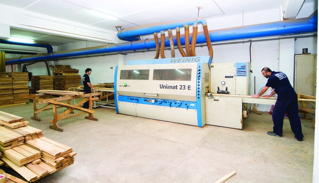 Operators feeding lumber into a WEINIG woodworking machine at the Bahar facility